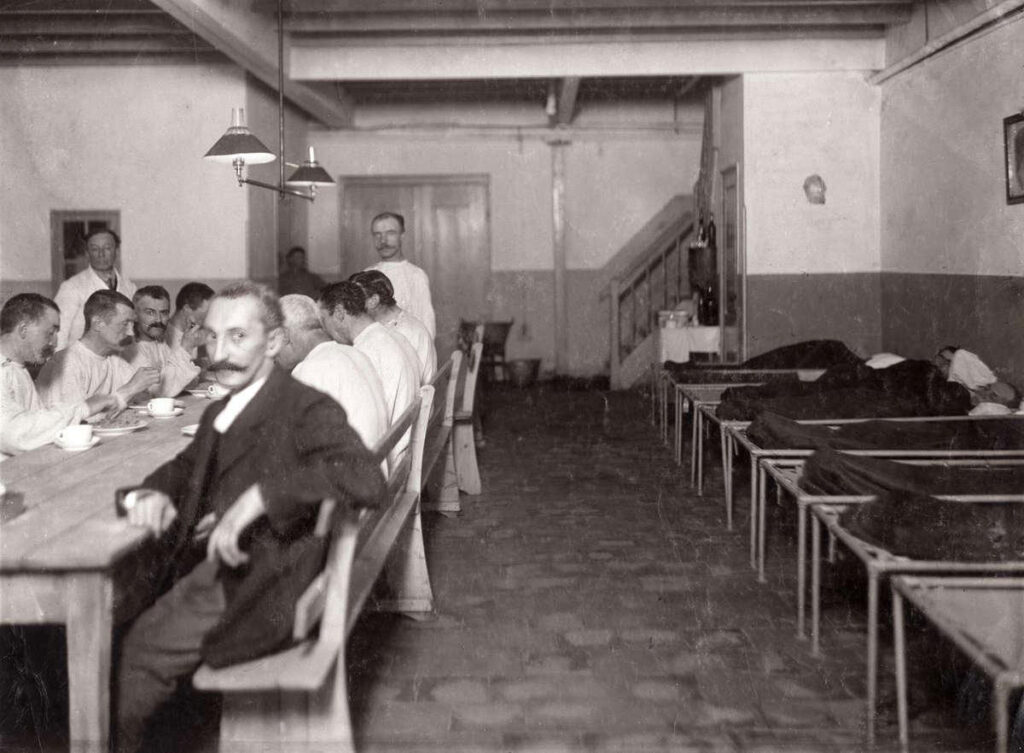 Mannen gebruiken een maaltijd alvorens ze naar bed gaan in het tehuis, aldus het tijdschrift Het Leven in een reportage over het Buitengasthuis van Hulp voor Onbehuisden in 1911.