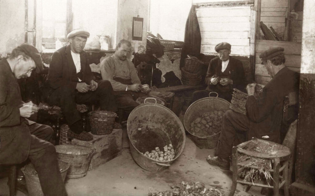 Mannen schillen aardappels in het Oud Buitengasthuis van Hulp voor Onbehuisden, foto uit Het Leven, 1925