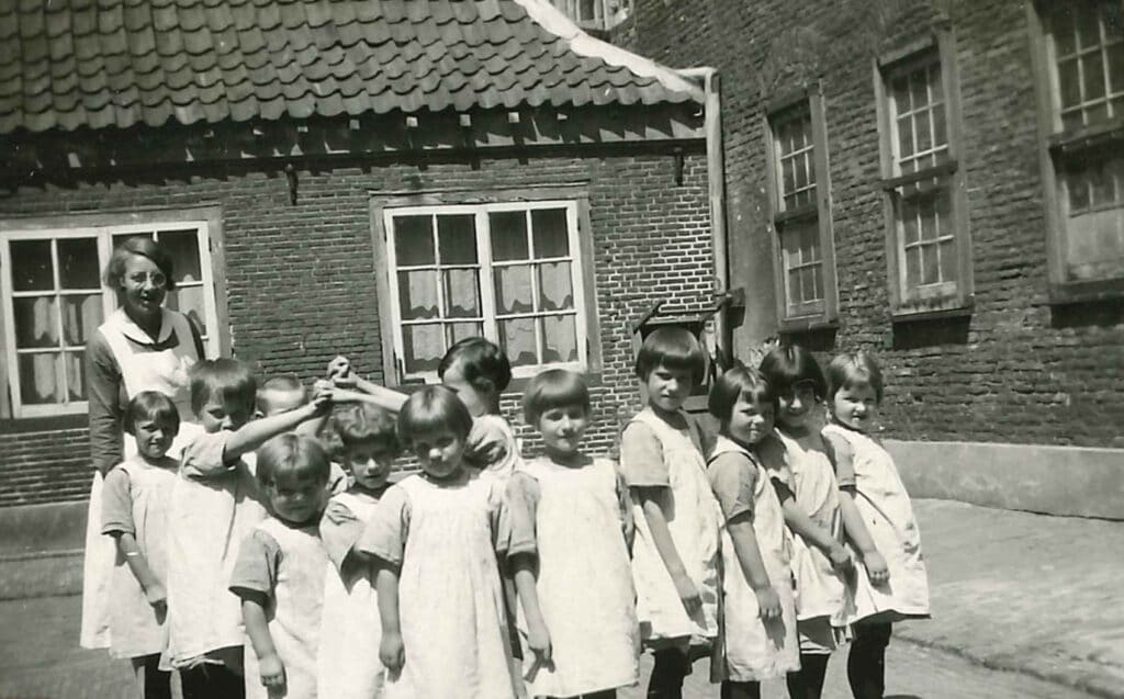 Kinderen en een zuster op de binnenplaats van het Oude Buitengasthuis van HvO, 1929