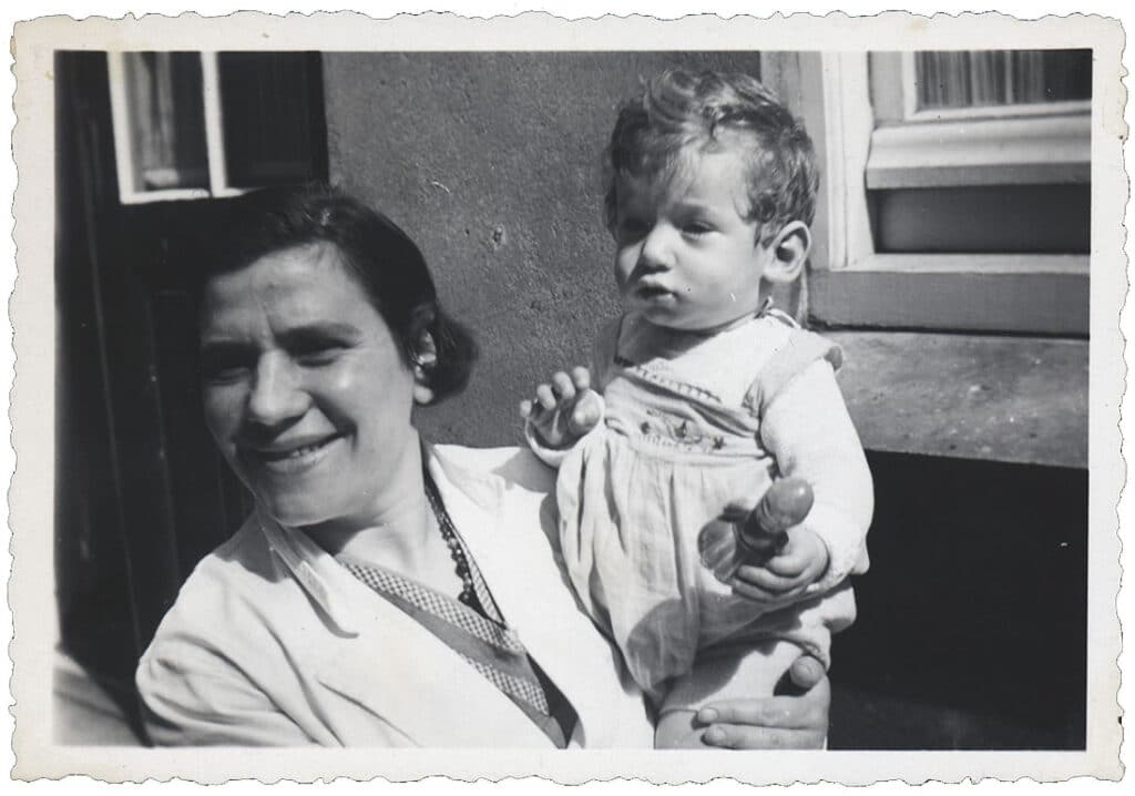 Op deze foto uit 1938 zien we de 1-jarige Salomon Mok op de arm van zijn 37-jarige moeder Lea Mok in de Roggeveenstraat van Hulp voor Onbehuisden, waar zij dan tijdelijk wonen. Beiden zijn in 1943 door de Duitsers vermoord in Auschwitz. De foto is afkomstig uit de collectie van het Joods Historisch Museum in Amsterdam en is gemaakt door Bep Gonkel die in die tijd bij HvO werkt.