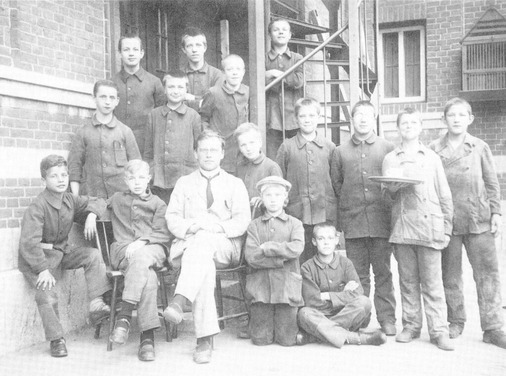 Jongens met een begeleider op de binnenplaats van het Observatiehuis van HvO in de jaren dertig