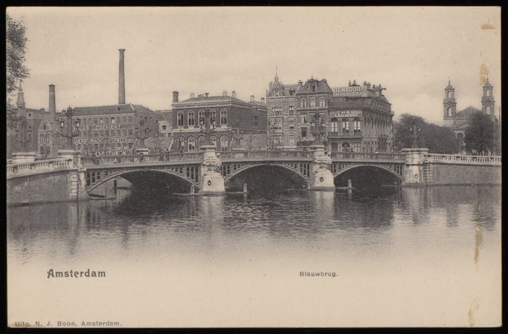 Op deze foto van circa 1900 uit het Amsterdamse Stadsarchief zijn op het gebouw achter de linkerboog van de Blauwbrug duidelijk de grote witte letters Volkslogement te lezen