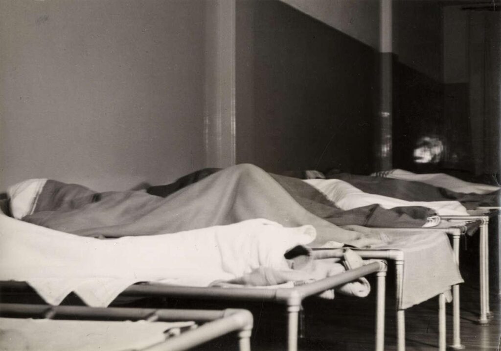 Nachtasiel van vereniging voor onbehuisden Amsterdam . Mensen liggen te slapen op bedden in de slaapzaal van het asiel, foto uit Het Leven, 1939