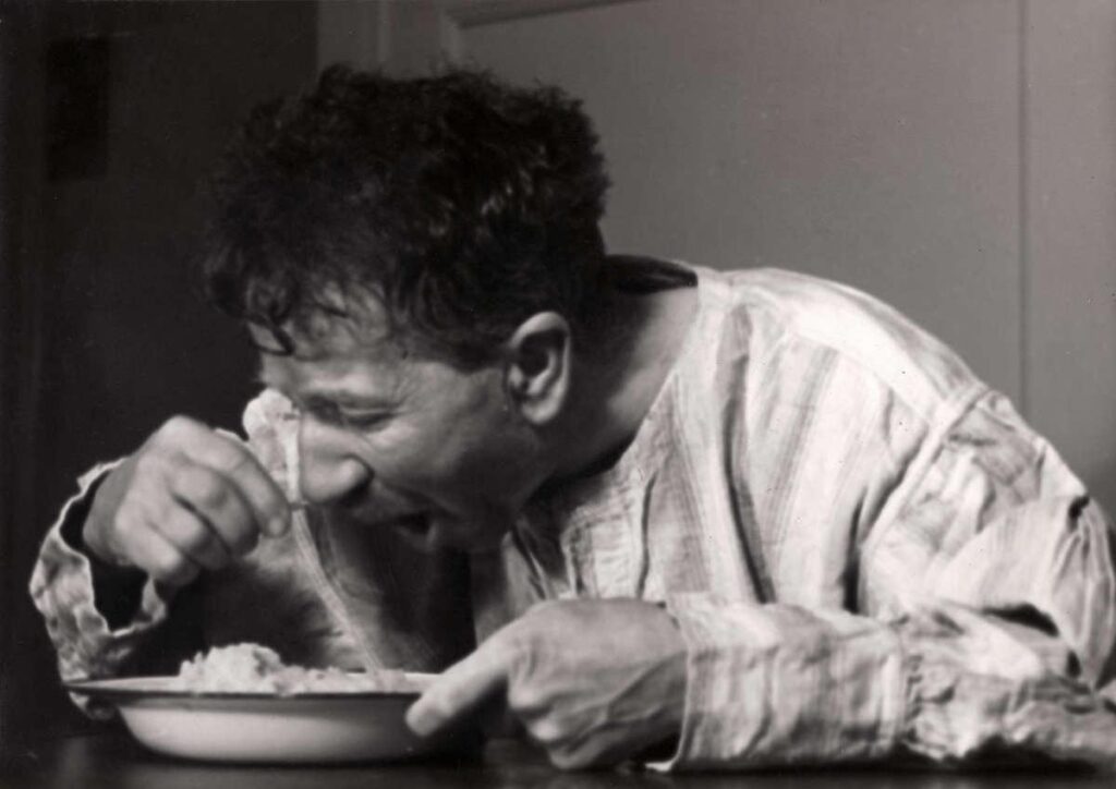 Nachtasiel van vereniging voor onbehuisden Amsterdam. Man is aan het eten van een bord in het asiel, foto uit Het Leven, 1939