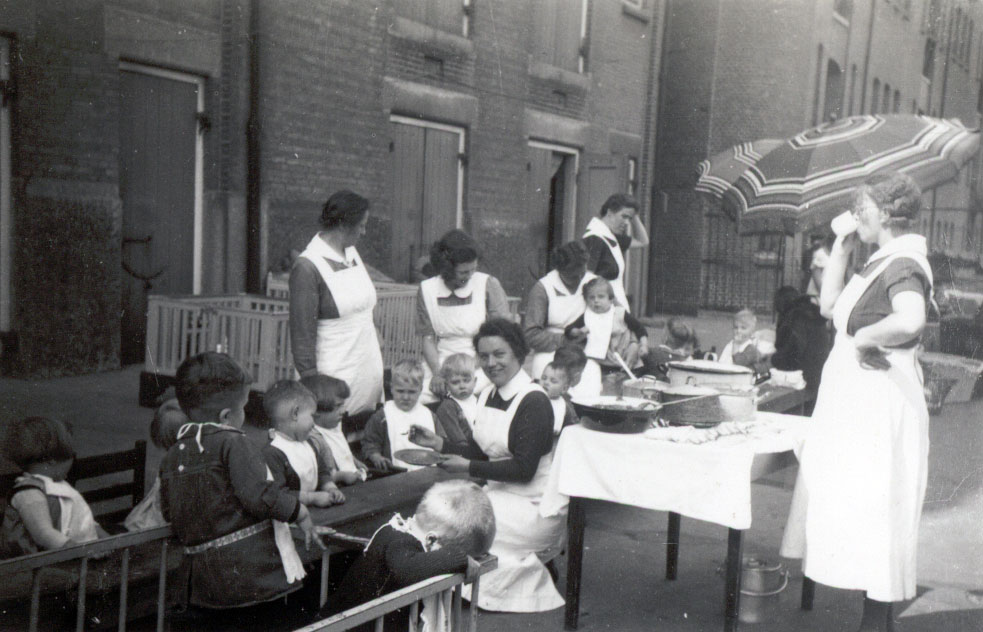 Kinderen en leidsters van HvO eten voor de schuilkelder in 1940