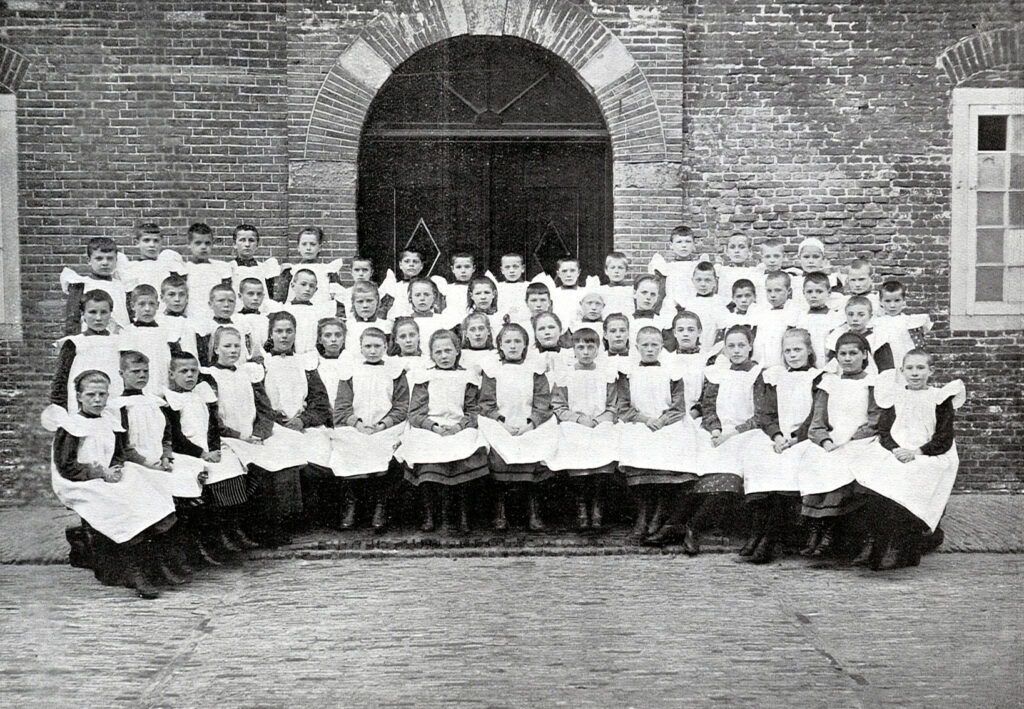 Meisjes poseren op de binnenplaats van het Oud Buitengasthuis van Hulp voor Onbehuisden in 1909