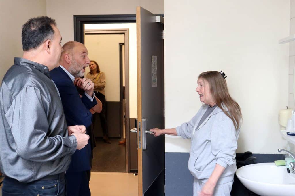 Een bewoonster van Passantenhotel Boerhaave laat de wethouder haar kamer zien