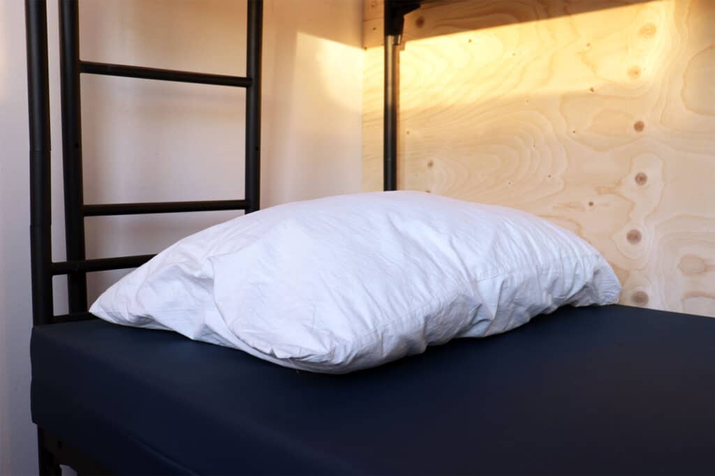 Een bed van de winteropvang met een houten tussenschot voor de privacy